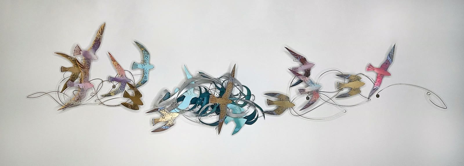 A wide sculptural wall piece by Katharine Leigh Simpson: pastel birds in flight, formed from reclaimed metal and wire