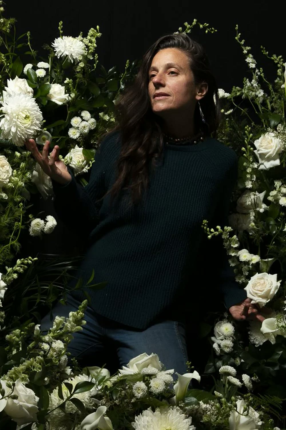 Featured artist Katharine Leigh Simpson standing among a wall of white florals she designed