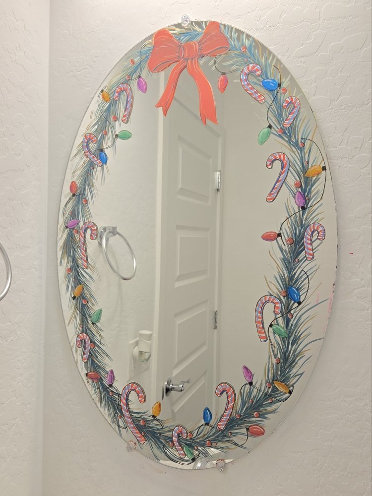 A mirror hand-painted with a candy-cane and pine Christmas wreath